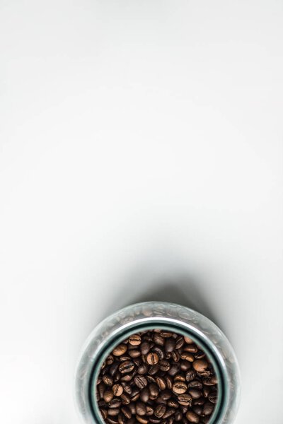top view of glass bottle with coffee beans on white