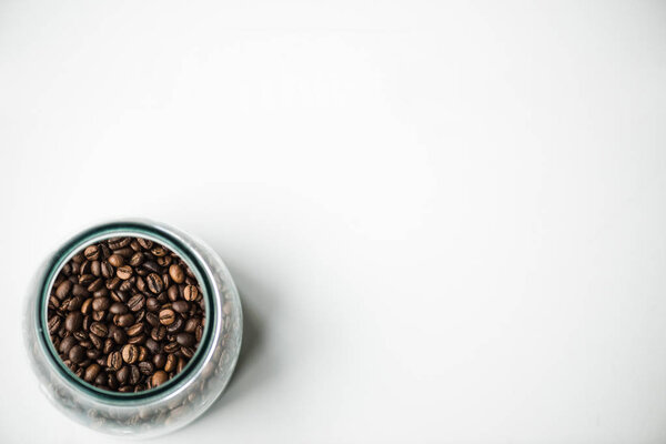 top view of glass bottle with coffee beans on white