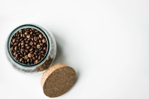 top view of glass bottle with coffee beans and cork on white