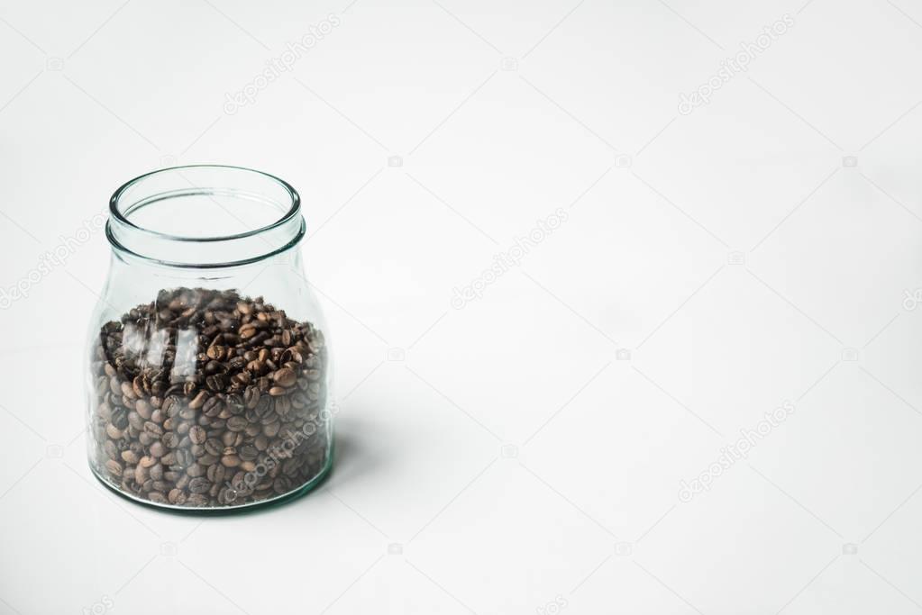 glass bottle with coffee beans on white