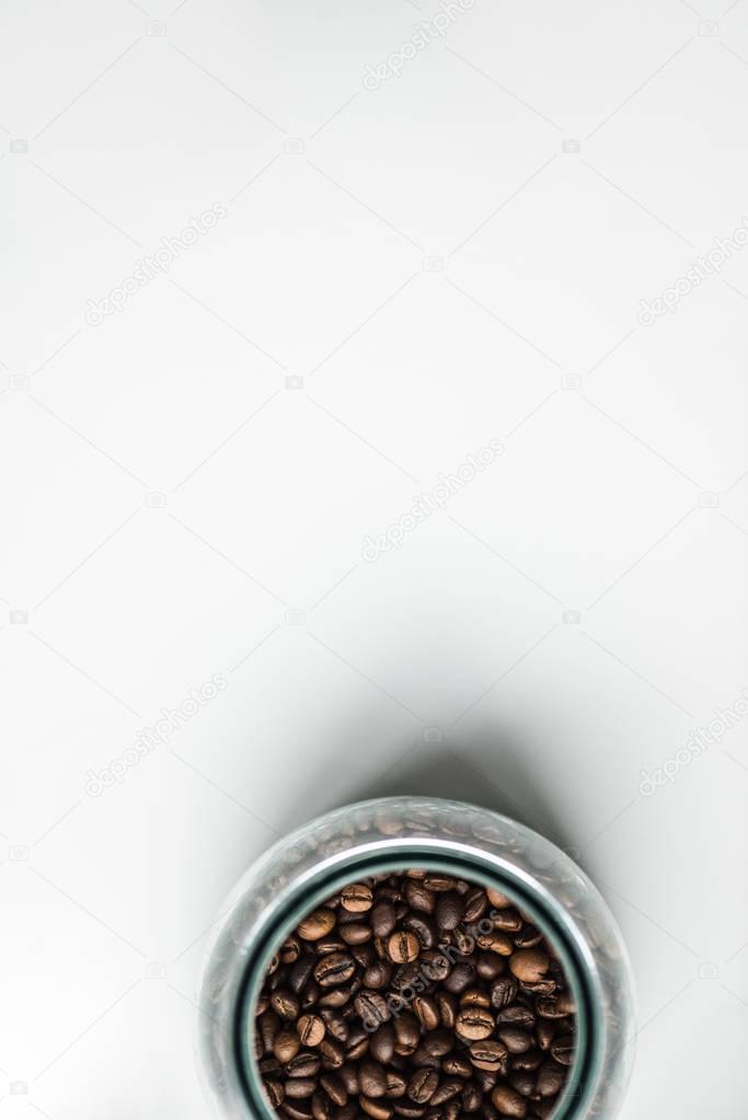 top view of glass bottle with coffee beans on white