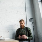 Handsome bearded businessman using smartphone in office