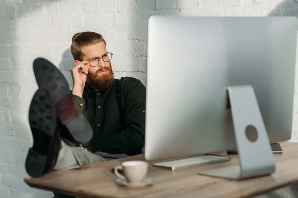 Geschäftsmann Sitzt Mit Beinen Auf Bürotisch Und Schaut Auf Computer — Stockfoto