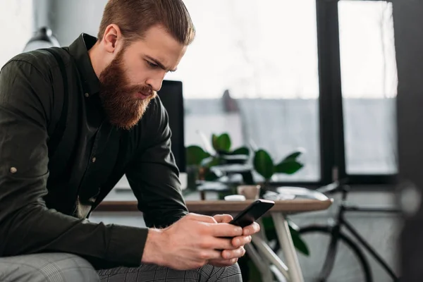 Gutaussehender Geschäftsmann Sitzt Und Schaut Aufs Smartphone — Stockfoto