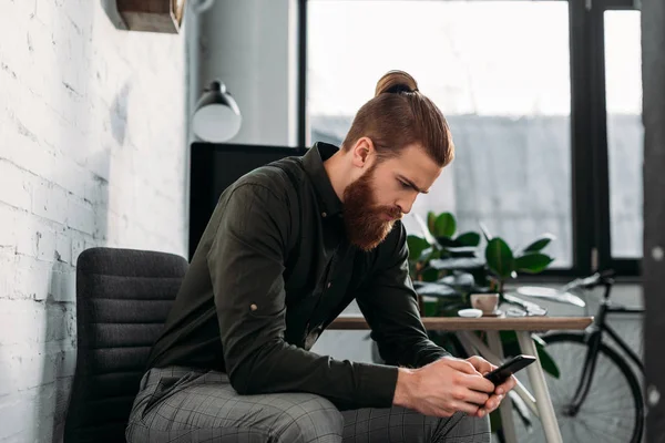 Pohledný Podnikatel Sedí Při Pohledu Smartphone — Stock fotografie