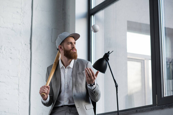 businessman throwing up baseball ball and holding baseball bat