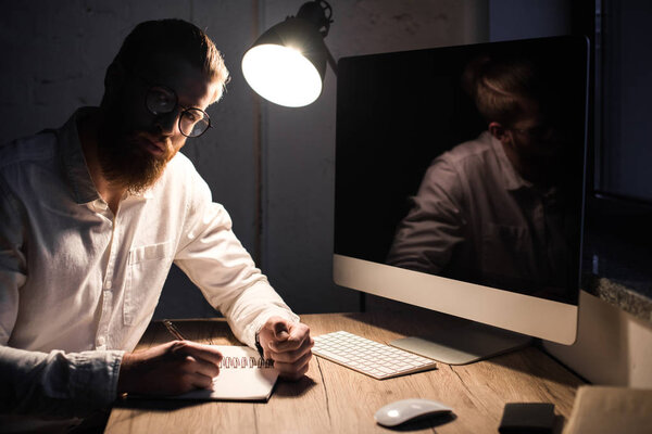 businessman sitting with notebook in office and looking at camera