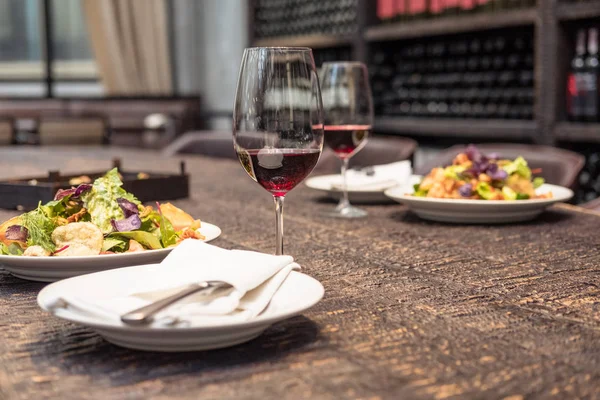 高級レストランでロマンチックな夕食のための素朴な木製のテーブルの上にワインのおいしいサラダ — ストック写真
