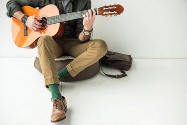 adam duvara yaslanmış ve akustik gitar çalmak kırpılmış görüntü