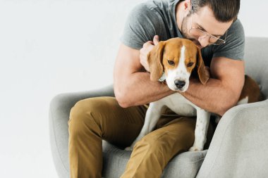 köpek sarılma ve üzerinde beyaz izole koltuk üzerinde oturan adam