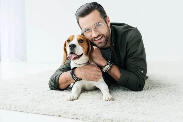 Glücklicher Schöner Mann Der Mit Hund Auf Teppich Liegt Und — Stockfoto