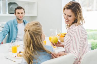 Mutlu bir aile evde kahvaltı yapıyor.