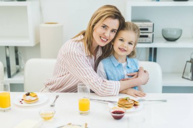 gülümseyen anne kucaklama kız evde kahvaltı sırasında