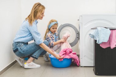 Anne ve kızı Çamaşırhane evde çamaşır makinesi koyarak yan görünüm