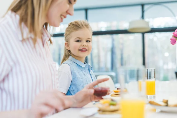 母と娘が一緒に家で朝食を持っていることの側面図  — 無料ストックフォト