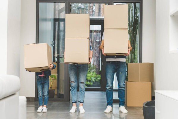 partial view of family holding cardboard boxes at new home, moving home concept