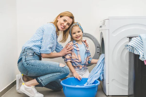 Madre Hija Mirando Cámara Mientras Ponen Ropa Lavadora Casa — Foto de Stock