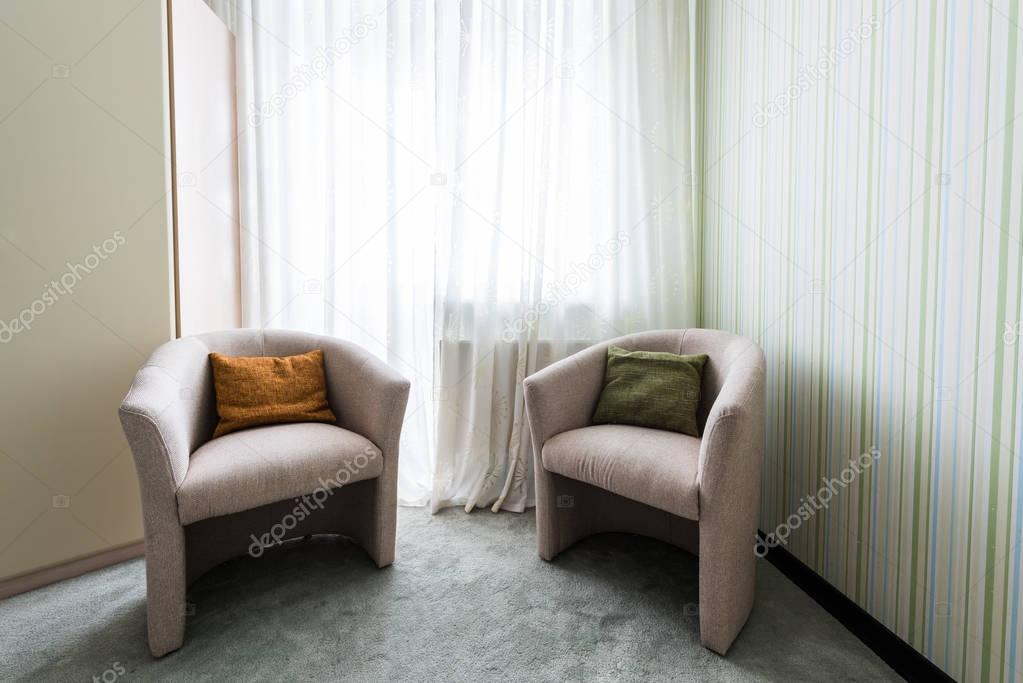 close up view of armchairs at window in room