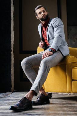 gözlük ve kanepede oturan takım elbise şık yakışıklı 