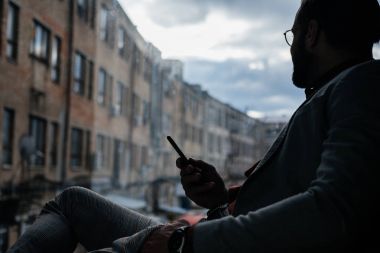 smartphone kullanarak ve pencerede oturup zarif adam silüeti