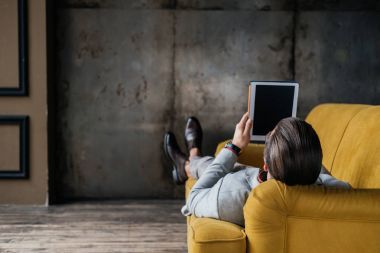 arkadan görünüşü şık adam kanepede çatı iç yalan dijital tablet kullanma