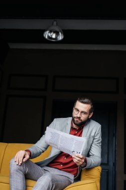 gazete okuma ve kanepede oturan şık elbiseli şık adam