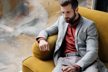 penceresinde sarı kanepede oturan moda yakışıklı adam