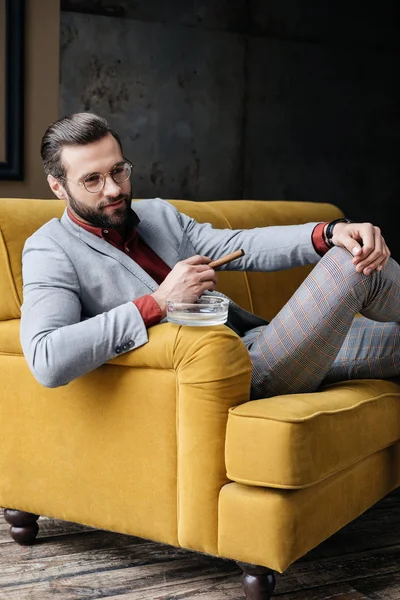 Schicker Gutaussehender Mann Mit Zigarre Und Aschenbecher Auf Couch Sitzend — Stockfoto