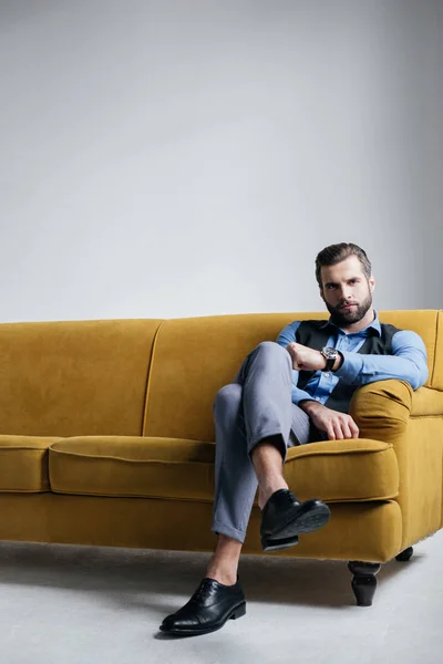 黄色のソファーに座っていたスタイリッシュなエレガントな男 — ストック写真