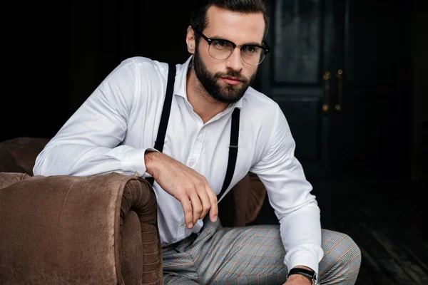 Gözlük Beyaz Gömlek Pantolon Askısı Koltukta Oturan Zarif Yakışıklı — Stok fotoğraf
