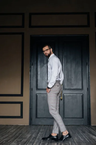 Модный Элегантный Мужчина Позирует Белой Рубашке Подтяжки Против Двери Лофт — стоковое фото