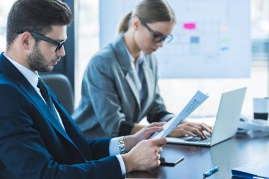 iş adamı ve iş kadını office belgelerinde bakarak yan görünüm
