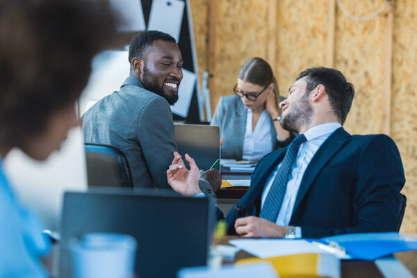 smiling multicultural businessmen talking in office