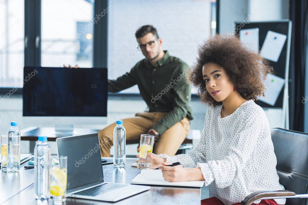 multicultural businessman and businesswoman looking at camera in office