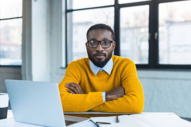 çapraz kolları ile oturma ve Office kamera bakıyor Afrika kökenli Amerikalı işadamı