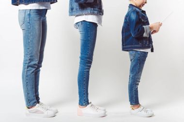 partial view of family and kid with tablet in similar denim clothing standing in row isolated on grey clipart