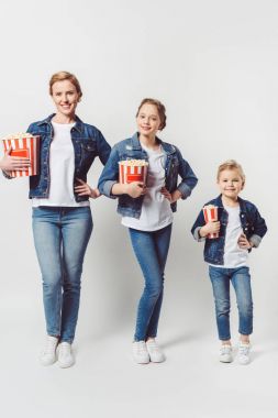 smiling family in similar denim clothing with popcorn isolated on grey clipart