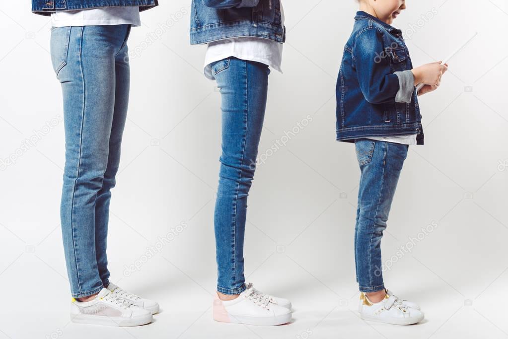 partial view of family and kid with tablet in similar denim clothing standing in row isolated on grey