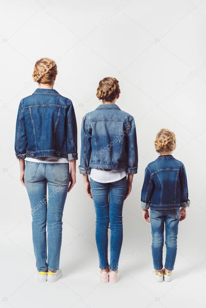 back view of family in similar denim clothing standing in row isolated on grey
