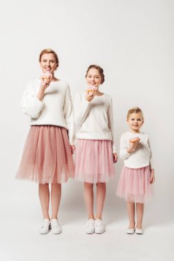 family in similar clothing with sweet doughnuts isolated on grey clipart