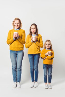mother and daughters holding cups of hot hoffee on white clipart
