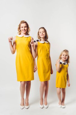 mutlu anne ve kızları benzer retro tarzı sarı elbiseler kameraya beyaz üzerinde seyir
