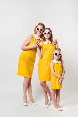 Anne ve kızı benzer retro tarzı elbiseler ve güneş gözlüğü üzerinde beyaz sarı