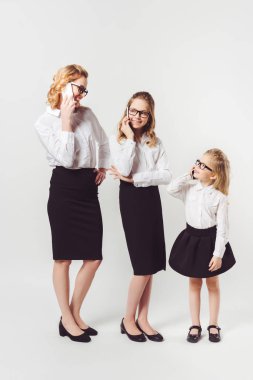 mother and daughters in similar businesswomen costumes on white clipart