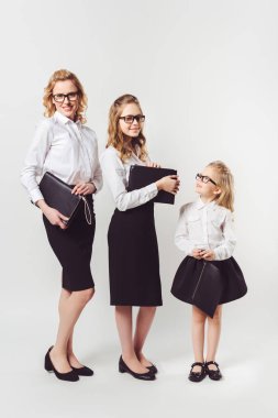 mother and daughters in similar businesswomen costumes with clutches on white clipart