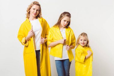 stylish beautiful mother and daughters in yellow raincoats on white clipart