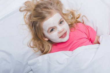 sevimli küçük çocuk güzellik maskesi ile yatakta yalan
