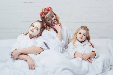 Anne ve kızı yatakta Güzellik yüz maskeleri ile