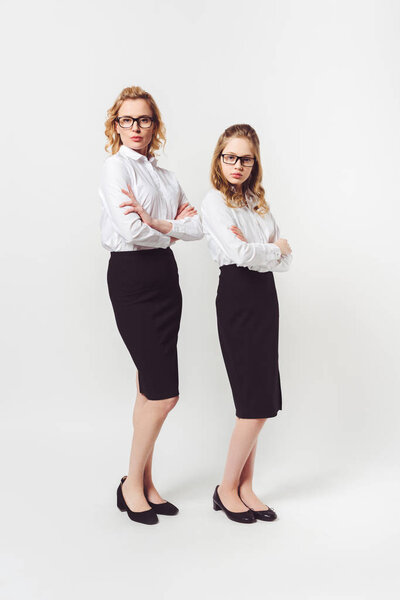 two businesswomen of different generations with folded arms on white