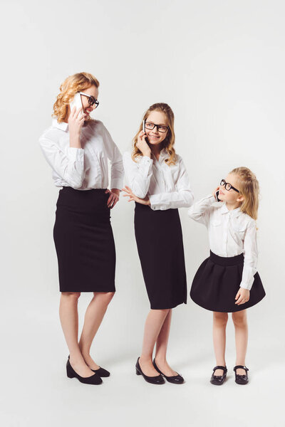 mother and daughters in similar businesswomen costumes on white